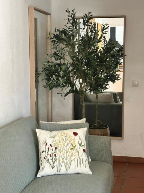 Aconchegante cantinho da villa Monte da Tojeirinha com cadeira estofada em verde, almofada bordada floral, espelho emoldurado e