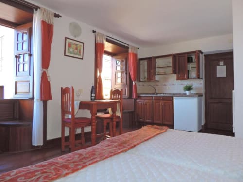Espacioso estudio en Casa Rural Los Helechos con muebles de madera roja, cocina y abundante luz natural