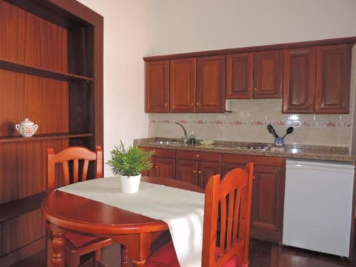 Cocina y comedor en apartamento Casa Rural Los Helechos con muebles de madera, encimera de granito y mesa de comedor