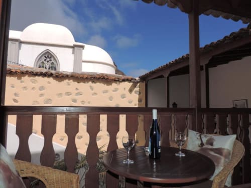 Vista del balcón en Casa Rural Los Helechos, Agulo con botella de vino y copas frente al patio interior tradicional
