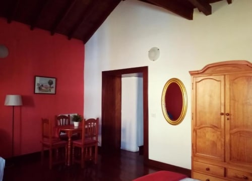 Estudio en Casa Rural Los Helechos en Agulo con paredes rojas, armario de madera, espejo dorado y mesa de comedor