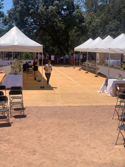 Instalación de carpa para evento exterior en Masías Can Trabal en Olerdola con mesas, sillas y fondo de árboles