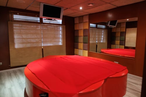 Habitación con cama roja, paredes marrones y espejos en el hotel Masias Can Trabal de Olerdola