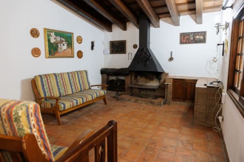 Sala de estar rústica en Masias Can Trabal de Olerdola con chimenea, asientos rayados, vigas vistas y decoración tradicional