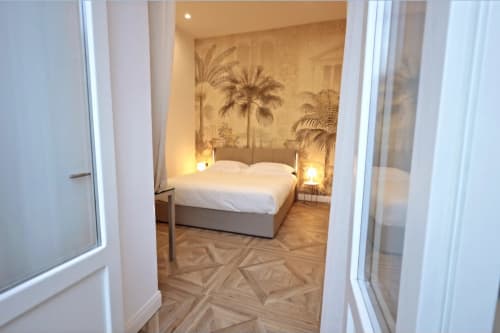Camera elegante presso Relais Santa Lucia sul Mare Napoli con letto king, carta da parati con palme, illuminazione calda e parquet in legno
