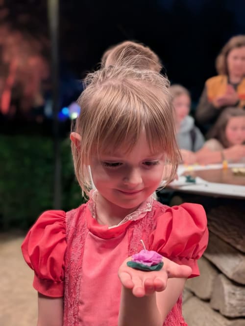 Young child in pink dress holding a small frog at Domaine De Campagnac, a charming BnB in Carsac-Aillac