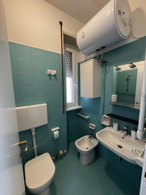 Bagno moderno della Porta Romana Suite Milano con piastrelle turchesi, doppio lavabo, wc e scaldacqua elettrico