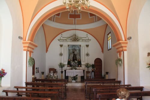 Interior de la capilla La Joya de Setenil con arcos naranjas, bancos de madera y altar en Setenil de las Bodegas