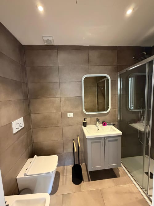 Bagno moderno della Porta Romana Suite Milano con lavabo, wc, doccia e specchio illuminato