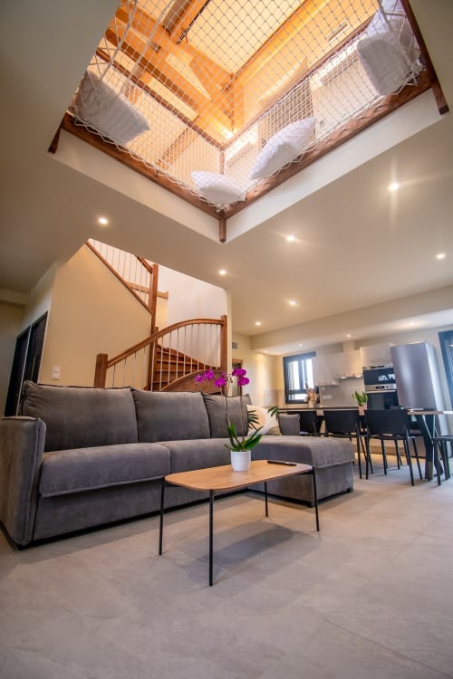Modern duplex living area at Lieu-dit Boulage with gray sofa, spiral staircase, and skylight in Marquefave