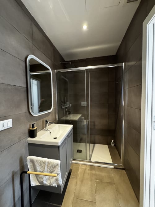 Bagno moderno della Porta Romana Suite Milano con box doccia, specchio LED e vanità grigia