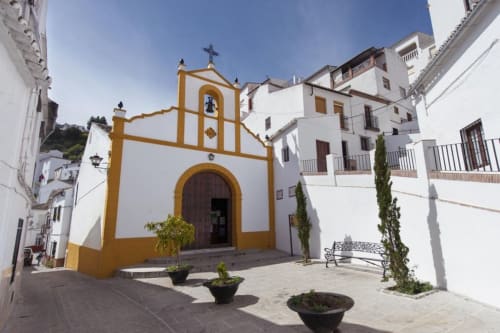 Capilla blanca y amarilla con cruz en la plaza de Setenil de las Bodegas, patio del hotel La Joya de Setenil