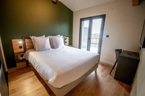 Modern bedroom at Lieu-dit Boulage hotel in Marquefave with queen bed, green accent wall, and terrace access