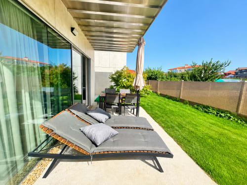 Terraza soleada con tumbonas en el apartamento Holibai de Baiona, con vistas al jardín cuidado y muebles de patio
