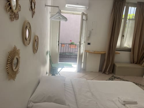 Camera luminosa al Lovelyloft Milano con letto bianco, porte balconate e piatti decorativi a parete
