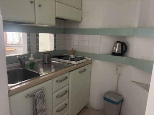 Cucina compatta dell'appartamento Lovelyloft Milano con pensili color crema, lavello in acciaio inox, bollitore elettrico e piastrelle verdi