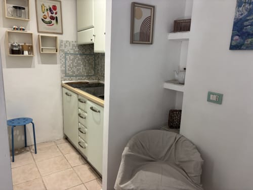 Compact Milan apartment kitchen and living area with compact kitchenette, white cabinetry, tiled backsplash, and furnished