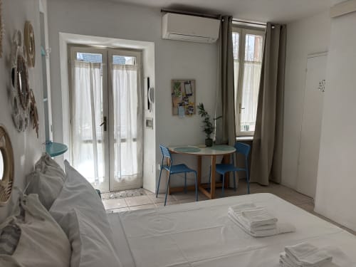 Bright modern bedroom at Lovelyloft Milano with blue chairs, round table, and garden view through double doors