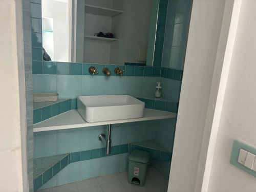 Modern bathroom with turquoise tile walls, white vessel sink, and mirror at Lovelyloft Milano apartment