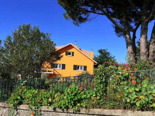 Bright yellow hostel building with flowering garden fence in Caminha, Portugal