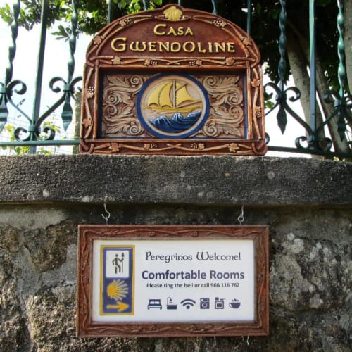 Casa Gwenodoline hostel sign in Caminha, Portugal featuring sailing ship emblem and pilgrims welcome plaque