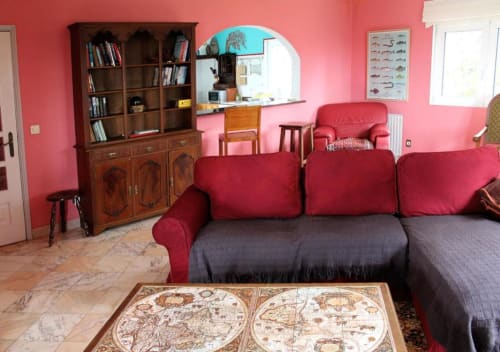 Colorful living room at Bom Caminha hostel in Caminha with red sofa, wooden bookcase, and vintage world map table