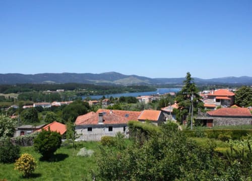 Bom Caminha hostel in Caminha, Portugal with red-roofed buildings overlooking a river valley and mountains