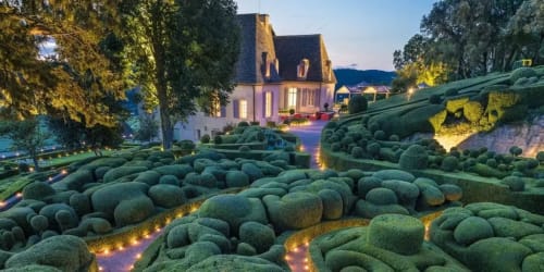Domaine De Campagnac, gîte de charme au crépuscule avec jardins de topiaires illuminés et manoir à toit mansardé à Carsac-Aillac, France