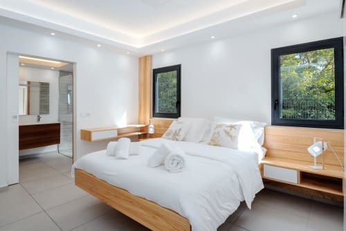 Modern bedroom at Vista Del Mar hotel in Sainte-Anne with wooden bed, white linens, ensuite bathroom, and garden views