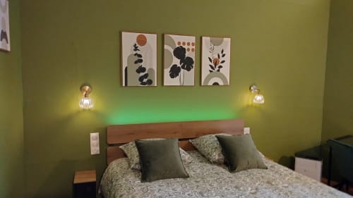Chambre moderne des Troglos de Beaulieu avec murs verts, lit en bois, luminaires suspendus et art botanique abstrait