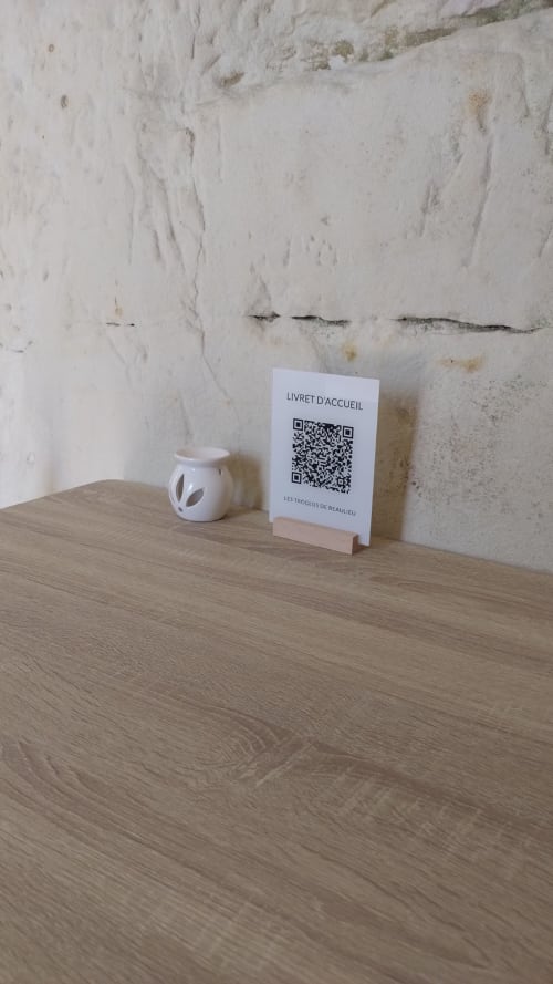 Carte de bienvenue avec code QR sur table en bois dans la chambre d'hôtes Les Troglos de Beaulieu