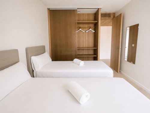 Moderno dormitorio doble en Holibai ModulSuites en Baiona con armario de madera y ropa blanca