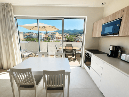 Cocina y comedor modernos con vista a la terraza y las montañas de Baiona en ModulSuites