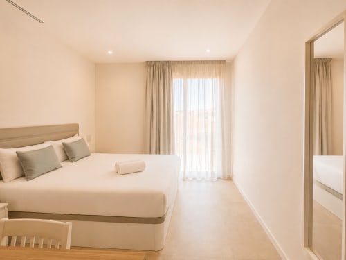 Dormitorio moderno en Holibai ModulSuites de Baiona con cama de matrimonio, vistas a la ciudad, acceso a terraza y mobiliario contemporáneo