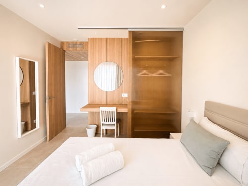 Moderno dormitorio en Baiona con escritorio de madera, espejo circular y baño privado en Holibai ModulSuites