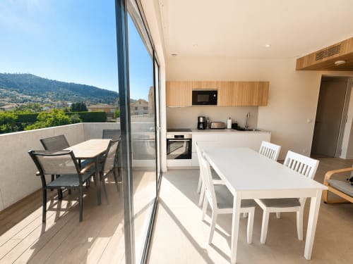 Moderno interior de apartamento en Baiona con cocina abierta, mesa de comedor blanca y terraza con vistas a la ciudad