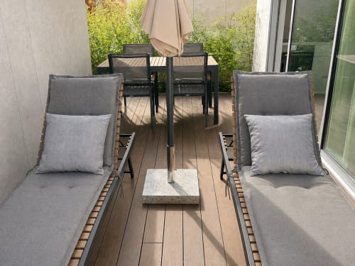 Terraza moderna en apartamentos Holibai en Baiona con tumbonas, mesa de comedor, sombrilla y muro verde exuberante