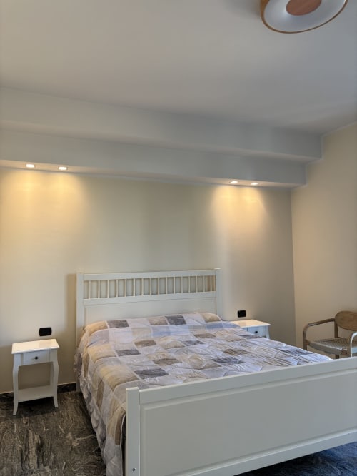 Camera da letto moderna presso Casa Vacanze Luna a Seriate con letto bianco, comodino e luci calde al soffitto