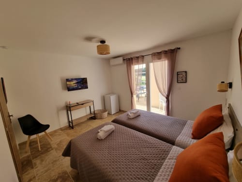 Twin bedroom with pool view at L'Orée du Ventoux, Crillon-le-Brave. Orange pillows, brown bedding, modern desk, glass doors