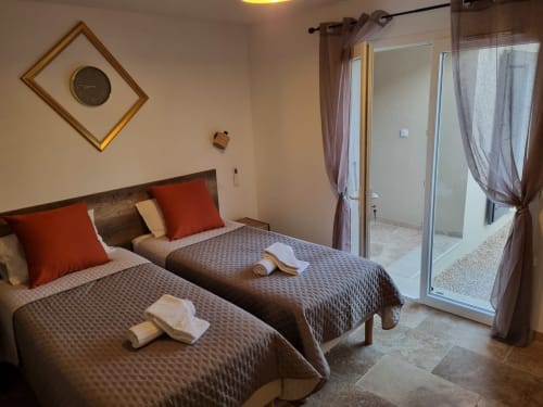 Chambre twin à L'Orée du Ventoux avec coussins orange, vue sur la piscine et salle de bains privative à Crillon-le-Brave