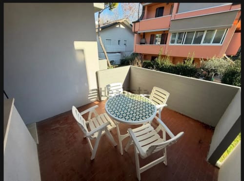 Patio privato con tavolo rotondo, sedie bianche e vista sul giardino a Romagnapartments a Cervia, Italia