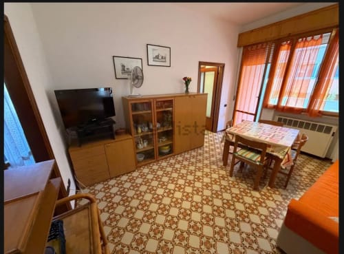 Luminosa sala con mobili in legno, TV, tavolo da pranzo e pavimento in cotto a Romagnapartments, Cervia