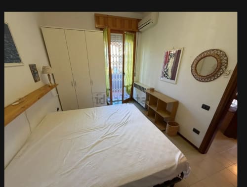 Camera da letto luminosa con letto matrimoniale, armadio, porte sulla veranda e vista sul giardino a Romagnapartments a Cervia