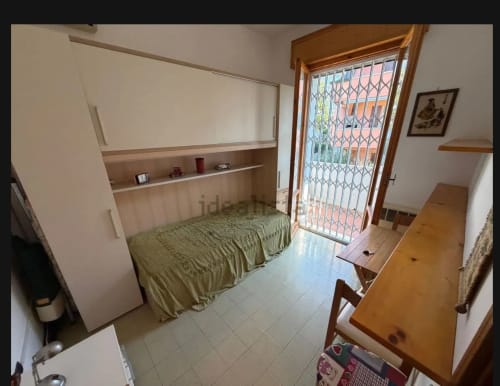 Camera accogliente presso Romagnapartments Cervia con letto singolo, scrivania in legno e accesso alla terrazza sul giardino