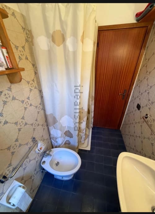 Bagno di Romagnapartments Cervia con lavabo blu, tenda doccia, bidet e pavimento in piastrelle scure