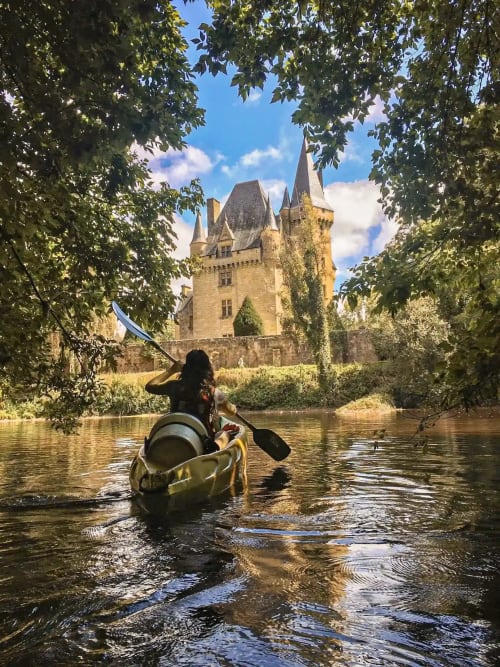 Kayakiste pagayant sur la rivière vers le château médiéval du Domaine de Campagnac, Carsac-Aillac, France