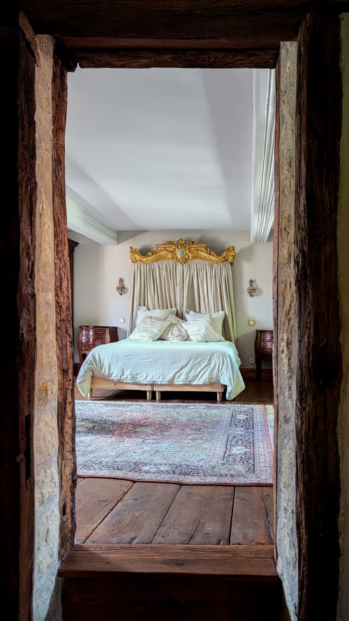 Rustic wooden doorway opening to elegant bedroom with golden canopy bed at Domaine Au Fil Du Temps, Bouxwiller