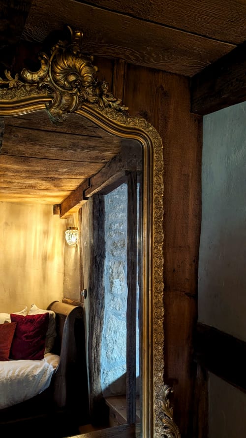 Ornate gold-framed doorway revealing a cozy bedroom with red pillow at Domaine Au Fil Du Temps, Bouxwiller