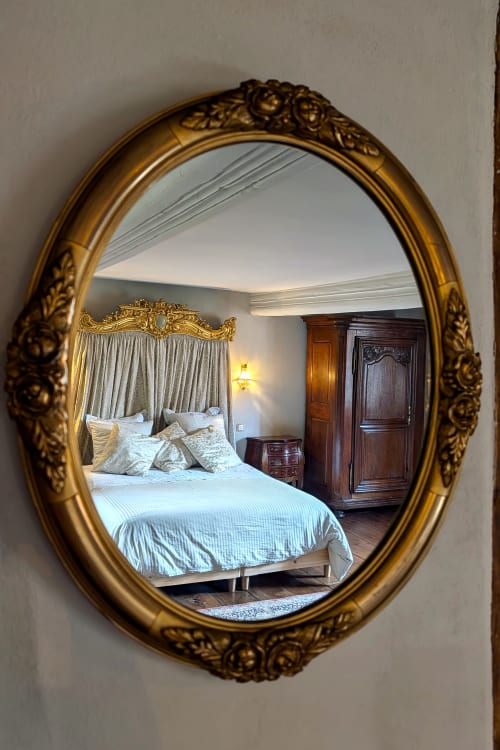 Ornate gold oval mirror reflecting Suite Ana Katharina bedroom at Domaine Au Fil Du Temps, Bouxwiller