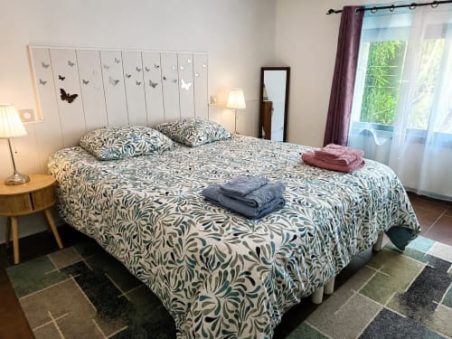 Dormitorio espacioso en Maison D'hôtes Coeur D'hérault con ropa de cama estampada, ventanas con vistas al jardín y comodidades modernas